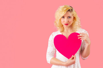 Studio portrait of a beautiful young woman holding pink heart, romantic love, dating and Valentine's Day concept