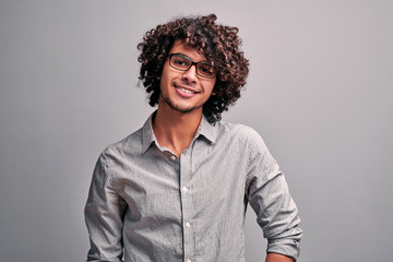 Obraz premium Waist up portrait of handsome eastern guy in gray shirt wearing eyeglasses on isolated gray background.