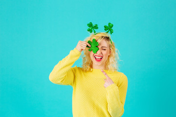 Studio portrait of a smiling woman holding shamrock covering one eye having fun, with St. Patrick's...