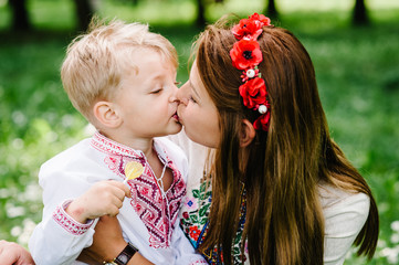 Mother kissing son with candy.  Happy funny family on the background grass on nature. Close up.