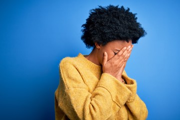 Fototapeta na wymiar Young beautiful African American afro woman with curly hair wearing yellow casual sweater with sad expression covering face with hands while crying. Depression concept.