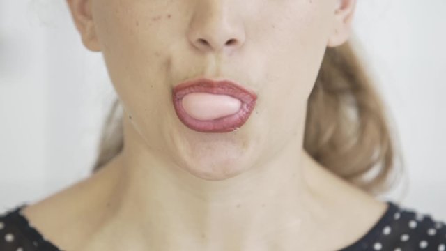 close up of blonde caucasian young girl with red lips chewing gum and blowing bubbles , hipster pop footage, black shirt
