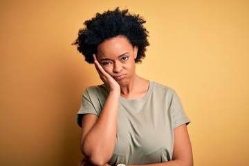 Fototapeta na wymiar Young beautiful African American afro woman with curly hair wearing casual t-shirt thinking looking tired and bored with depression problems with crossed arms.