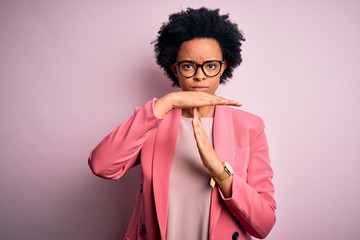 Young beautiful African American afro businesswoman with curly hair wearing pink jacket Doing time...