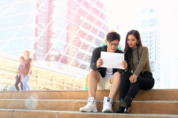 Young Asian tourist couple traveling together. Travelers with backpack holding a map and discussing...