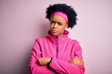 Fototapeta na wymiar Young beautiful African American afro sportswoman with curly hair wearing pink sportswear skeptic and nervous, disapproving expression on face with crossed arms. Negative person.