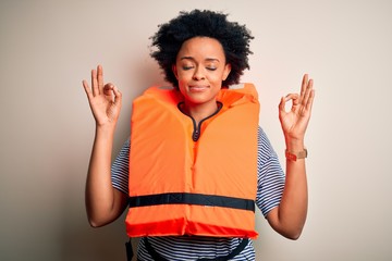 Young African American afro woman with curly hair wearing orange protection lifejacket relax and...