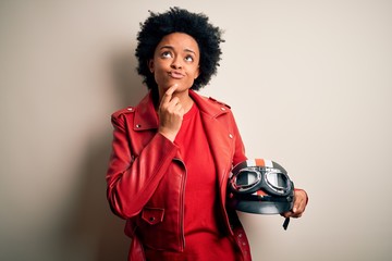 Young African American afro motorcyclist woman with curly hair holding motorcycle helmet Thinking...