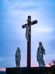 A Crucifix Statue With Two Statues of Woman Alongside