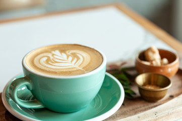 Coffee hot latte art serve in green coffee cup with brown sugar and snack.