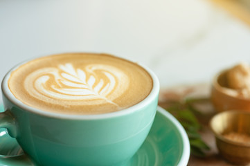 Coffee hot latte art serve in green coffee cup with brown sugar and snack.