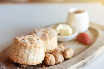 Fresh scones butter and strawberry jam serve on wooden tray, food stylish.