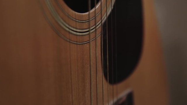 Tilt Up Of A Yellow Acoustic Guitar From The Bridge To The Soundhole - Close Up Shot