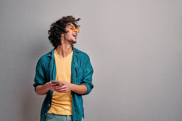 Curly handsome student using smartphone