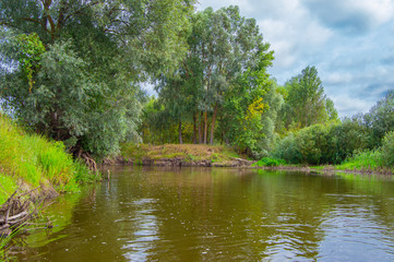 Photo from the boat. Turn of River a right angle with a steep bank with trees on it. Landscape of...