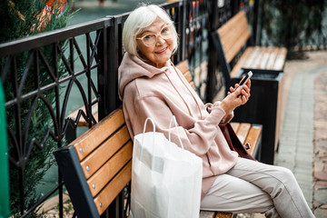 Happy aged woman with cell phone outdoors stock photo