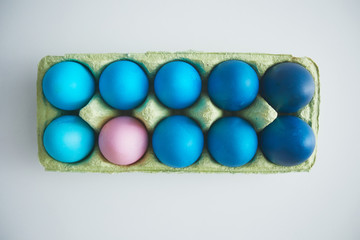 Above view of blue Easter eggs in crate with pastel pink accent arranged in minimal composition on...