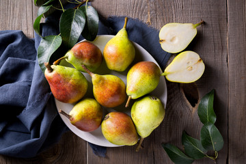 Ripe pears in a bowl and gray cloth on on a wooden table. Harvest concept