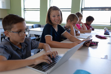 Fototapeta premium Group of schoolchildren sitting at desks in an elementary school classroom