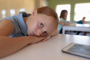 Schoolgirl leaning on her desk in an elementary school classroom