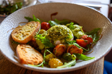 Vegetarian italian food, fresh vegetables salad with white soft burrata cheese and green pesto