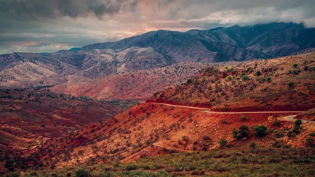4K UHD time lapse cinemagraph / seamless video loop of evening clouds moving above the red soil, stones and rocks in the Atlas mountains in Morocco on the way to Taroudant.