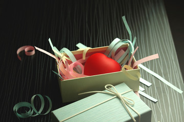 Red heart in blue gift box with shredded paper on black wood table, giving love as a present on Valentine's day concept