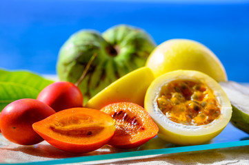Naklejka na ściany i meble Fresh ripe yellow passion fruit, cherymoia and tamarillo on blue sea background