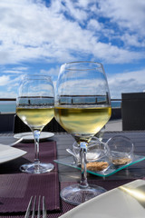 Table served for dinner on outside terrace with glasses of cold white wine and sea view