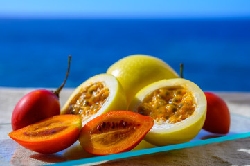 Fresh ripe yellow  passion fruit and tamarillo on blue sea background