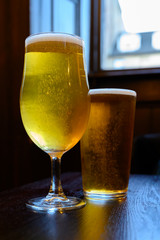 Misty glasses with two pints of cold Scotch ale, amber pale ale, lager draft beer in English pub