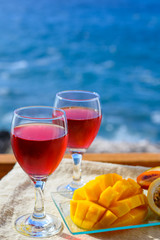 Two glasses with rose wine served outdoor with exotic fruits on tropical island La Palma, Canary islands, Spain with beautiful blue ocean view