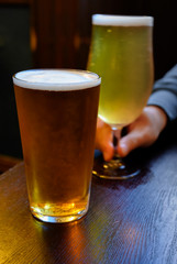 Misty glasses with two pints of cold Scotch ale, amber pale ale, lager draft beer in English pub