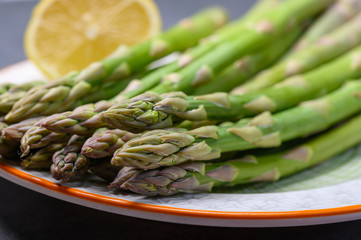 Bunch of fresh green raw organic asparagus with lemon ready to cook