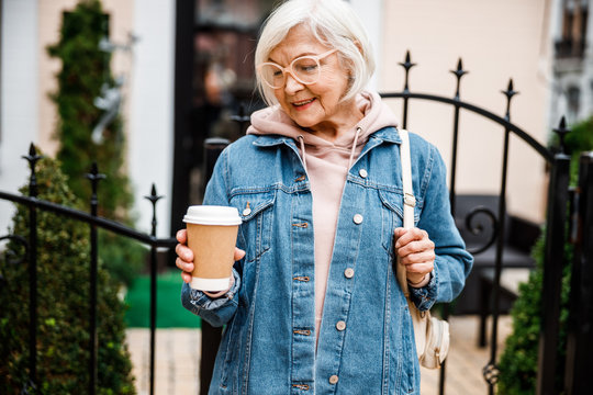 Jolly seniour woman with cup of hot drink stock photo