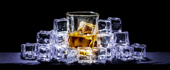 Whiskey on the rocks, whiskey glass, ice cubes on a slate board