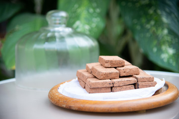nama brown chocolate and powder on white paper and wooden plate on pink glass table and glass cover with green leaf tree background stock photo