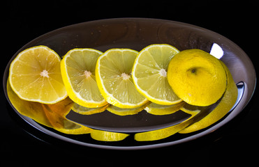 yellow lemon slices on silver plate, cooking still-life with mirroring reflection (close-up detail...