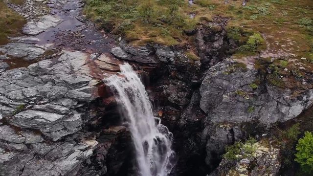 Aerial, drone shot panning over a waterfall, near the Sautso canyon, on a dark, overcast day, in Alta, Finnmark, north Norway