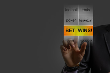 Futuristic gambling concept. Young man wearing vr glasses placing bets online touching virtual digital sensor screen with bookmaker's website interface. Front view.