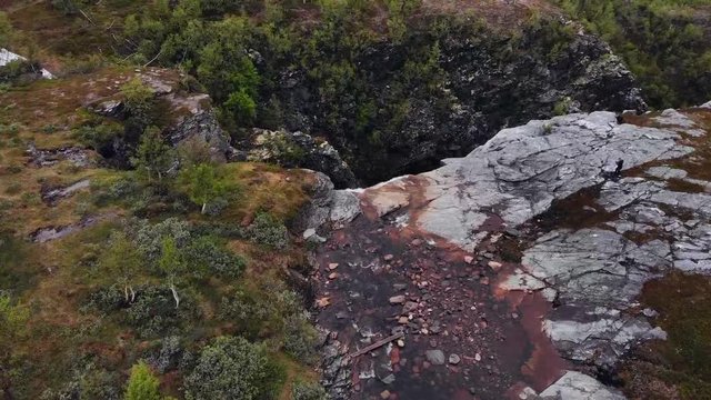 Aerial, tilt, drone shot overlooking a waterfall, near the Alta canyon, on a gloomy, overcast day, in Alta, Finnmark, north Norway