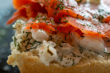  Half a roll topped with salmon and shrimp, with dill and coarse sea salt, close-up