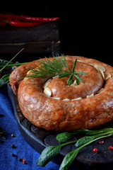 Roasted pork sausage with garlic served on the dark wooden board. Ukrainian cuisine meal