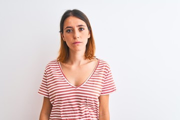 Fototapeta premium Beautiful redhead woman wearing casual striped red t-shirt over isolated background Relaxed with serious expression on face. Simple and natural looking at the camera.