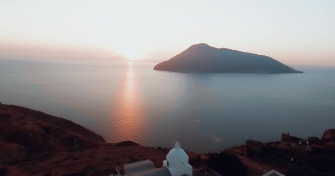 Drone panoramic view of the volcano in the blue Mediterranean sea of Lipari, Sicily. Drone is flying around houses on the cliff top, showing a stunning seascape with sunset crazy colors