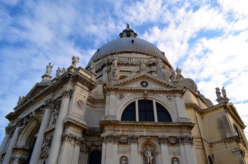 lower view of the part of the Church complex with a Central dome, semi-arched window, decorated with many reliefs and statues on the background of moving clouds in the sky