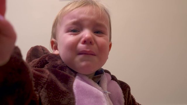 Toddler boy upset and crying starts to calm down.