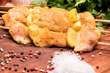 raw chicken skewers marinated with lemon on a wooden board