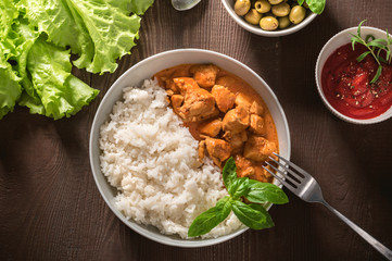 Indian curry chicken with basmati rice in bowl with spices and herbs