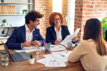 Group of business workers smiling happy and confident. Speaking with smile on face working together using laptop at the office.